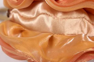 Vue macro du tissu en soie orange-rouge avec des plis de pétales et une texture satinée