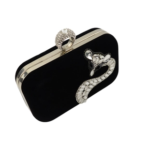 Detailed view of fox rhinestone emblem and crystal ring clasp on black velvet evening bag