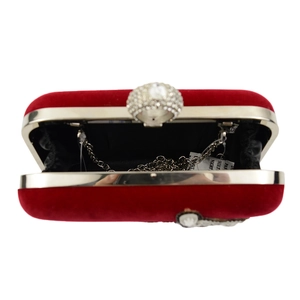 Detail of red velvet clutch bag with silver metal chain and sparkling crystal ring clasp