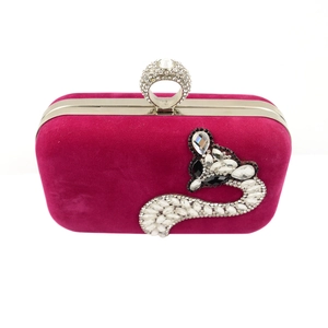 Macro detail of fuchsia velvet clutch bag with fox rhinestone pattern and ring clasp