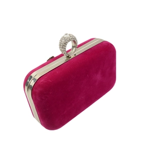 Close-up of a rose red velvet clutch with a crystal-encrusted ring clasp and silver trim