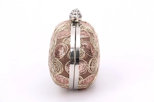 Detail of oval lace clutch bag featuring pink sequins, gold embroidery and rhinestone clasp