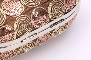 Detailed macro view of sequin rose embroidery and metallic frame on a clutch bag