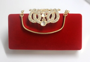 Détail d'une pochette de soirée en velours rouge avec fermoir couronne en strass