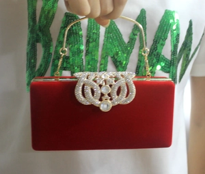 Détail de la pochette de soirée en velours rouge avec nœud en cristal et anse dorée