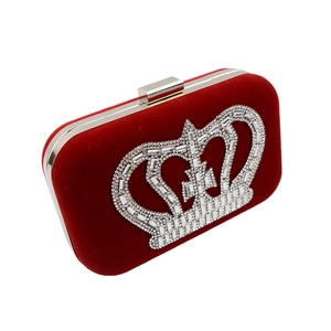 Detail view of red velvet evening clutch featuring a silver rhinestone crown motif