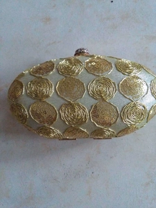Detail view of oval champagne gold evening clutch with sequins and rhinestone clasp
