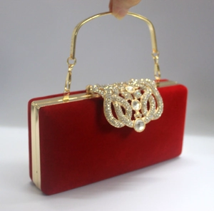 Détail de pochette en velours rouge avec fermoir couronne en strass et anse dorée