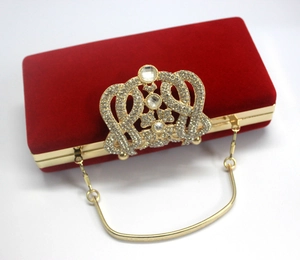Détail d'une pochette de soirée en velours rouge avec fermoir couronne et chaîne dorée