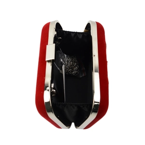 Detail of red velvet evening clutch featuring silver metal frame and chain strap