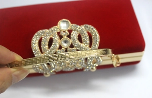 Détail de la pochette de soirée en velours rouge avec strass en forme de couronne et cadre doré