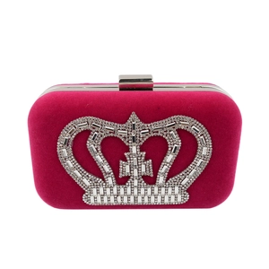 Macro view of rose red velvet dinner bag with sparkling rhinestone crown decoration