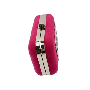 Detail view of fuchsia velvet evening clutch featuring silver metal frame and rhinestone trim