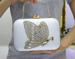 Detail of white leather clutch featuring a large multicolor crystal butterfly and gold handle