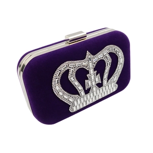 Detail of dark purple velvet clutch with crown rhinestone and silver metal frame