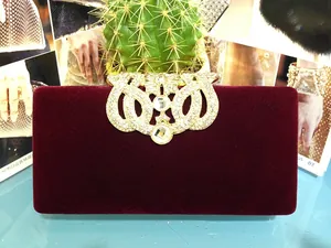 Détail du fermoir couronne doré avec strass blancs sur pochette de soirée en velours bordeaux