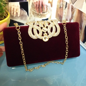 Détail de la pochette de soirée en velours rouge avec boucle couronne en strass dorés et chaîne