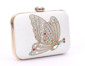 Macro detail of a white glitter evening clutch with a colorful rhinestone butterfly motif