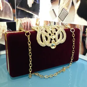 Détail de la pochette en velours bordeaux avec boucle dorée en strass et fine chaîne