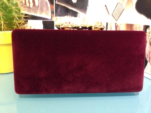 Détail de la pochette en velours bordeaux avec fermoir orné en métal doré