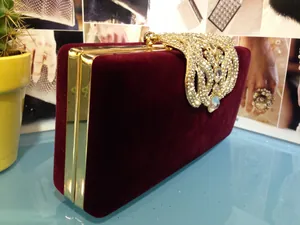 Détail d'une pochette de soirée en velours bordeaux avec fermoir doré orné de strass