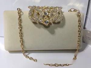 Détail du fermoir couronne en strass doré sur pochette de soirée en velours beige