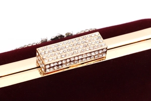 Détail macro d'une pochette de soirée en velours bordeaux avec fermoir en strass dorés