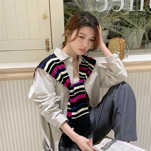 Close-up of a striped knit shawl draped over a beige shirt for a layered casual look