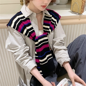 Detail of colorful striped knitted shawl draped over a classic grey button-up shirt
