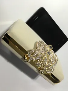 Détail de la pochette de soirée crème avec fermoir couronne en strass et téléphone
