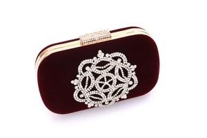 Détail de la pochette en velours bordeaux avec emblème en strass et cadre en métal doré
