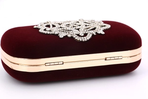 Détail de motif floral en strass argentés sur pochette de soirée en velours rouge