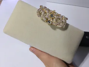 Détail d'une pochette en velours beige avec un grand fermoir doré orné de strass