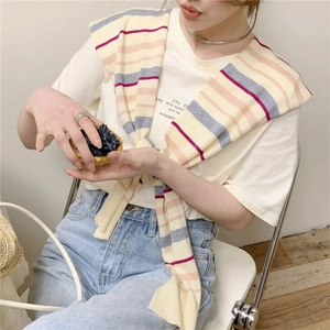 Detail of a colorful striped knit shawl draped over a white graphic tee for casual wear