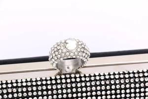 Detail of crystal ring clasp and rhinestone embellishments on black evening clutch bag