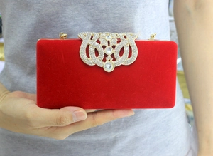 Détail d'une pochette de soirée en velours rouge avec fermoir couronne en strass