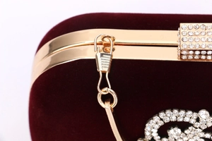 Détail de la pochette de soirée en velours rouge avec cadre doré et fermoir diamanté