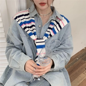 Detail shot of a blue, white and pink striped knit shawl styled over a denim shirt
