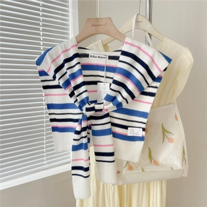 Striped knit shawl wrap for women over a dress in a bright, sunlit room setup