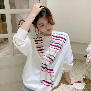 Detail of a white sweatshirt styled with a colorful striped knitted shawl accessory