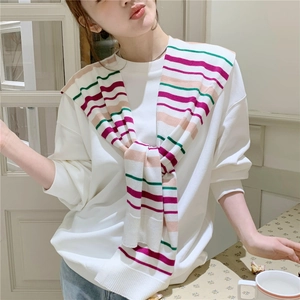 Detail of colorful striped knitted shawl knotted over a white sweatshirt for women