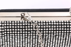 Close-up of lobster clasp and silver chain detail on a black rhinestone evening clutch bag