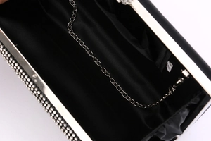 Detailed top view of black evening clutch bag with silver rhinestones and metal chain