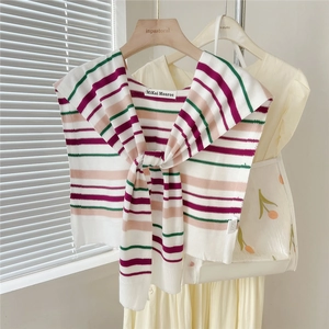 Detailed close-up of striped knit shawl with purple pink and green stripes on white fabric