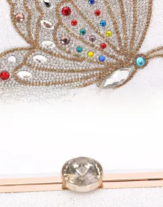 Macro detail of luxury white clutch with crystal butterfly and gold metal frame closure