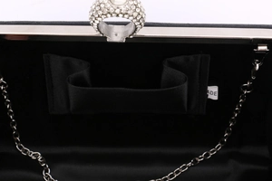 Macro shot of black satin evening bag interior with ring clasp and metal chain strap