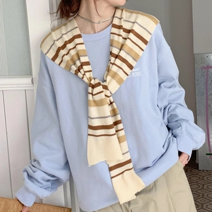 Detail of blue cotton sweatshirt paired with a striped knit shawl for layered styling