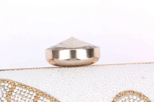 Macro detail of gold clasp with large crystal on white glitter bridal clutch bag