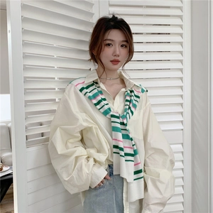 Detail of soft striped knit shawl tied over a beige oversized shirt with lapel collar