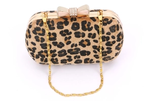 Detail of leopard print evening clutch featuring diamond bow clasp and gold chain strap